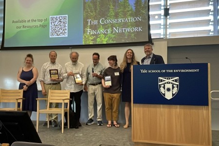 CFN staff and two of its co-founders posing with celebratory plaques for the 20th Boot Camp